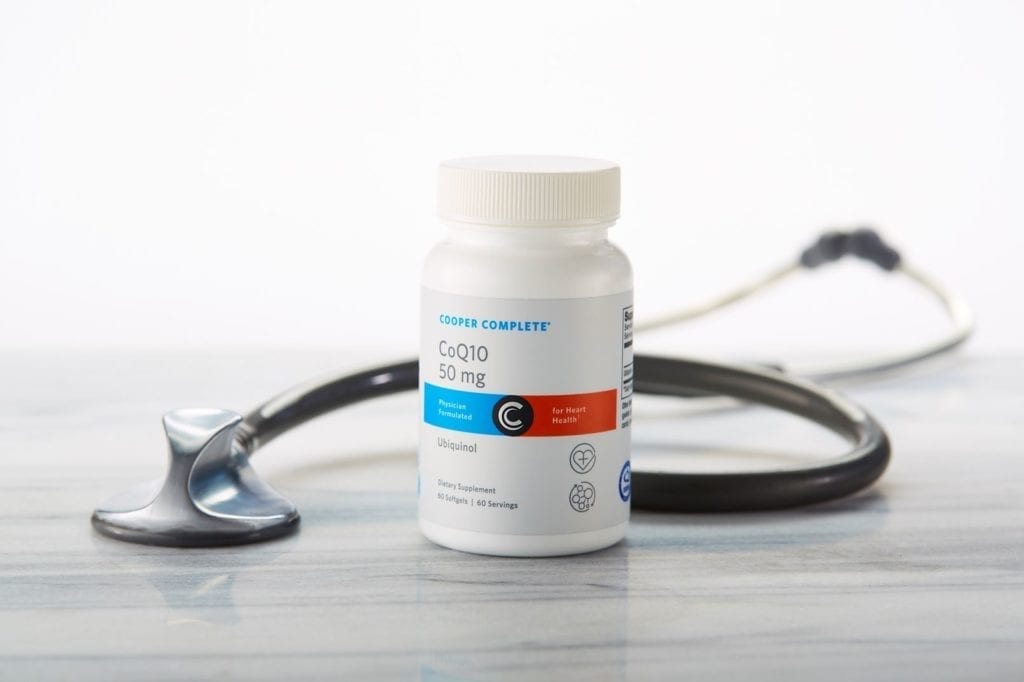 Cooper Complete CoQ10 50mg Ubiquinol dietary supplement bottle on a marble surface with stethoscope