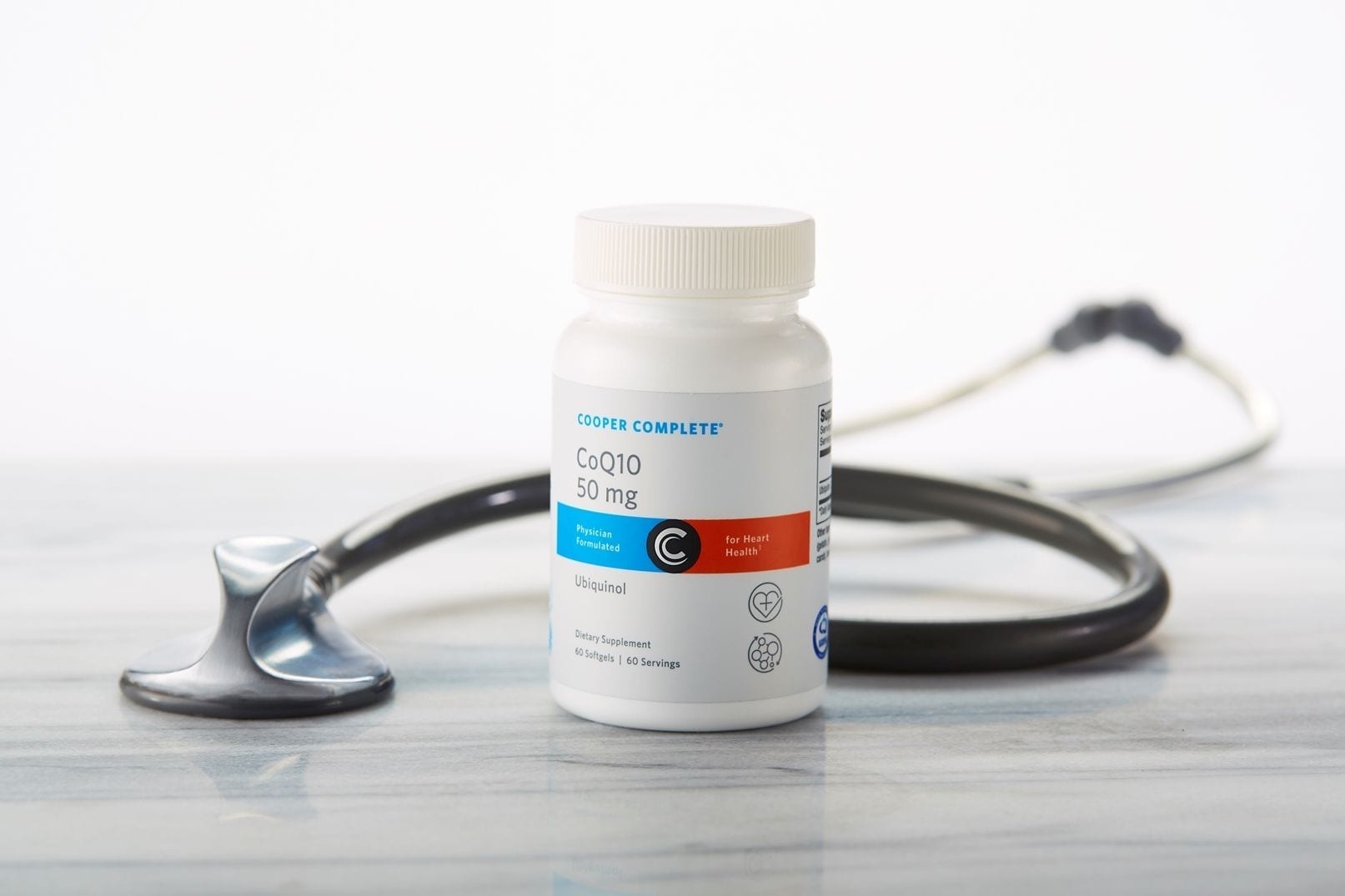 Cooper Complete CoQ10 50mg Ubiquinol dietary supplement bottle on a marble surface with stethoscope
