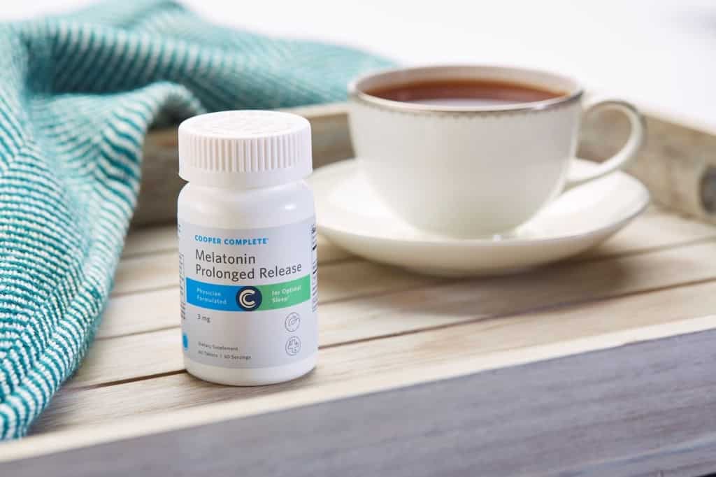 Complete Complete Melatonin Prolonged Release dietary supplement bottle with a cup and saucer of tea and napkin on a wooden tray