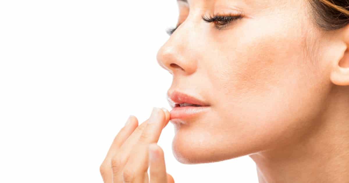 Photo of a woman applying a balm to her lips.