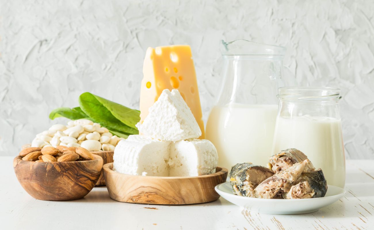 Photo of calcium sources, including sardines, milk and cream, beans and legumes, and cheese.