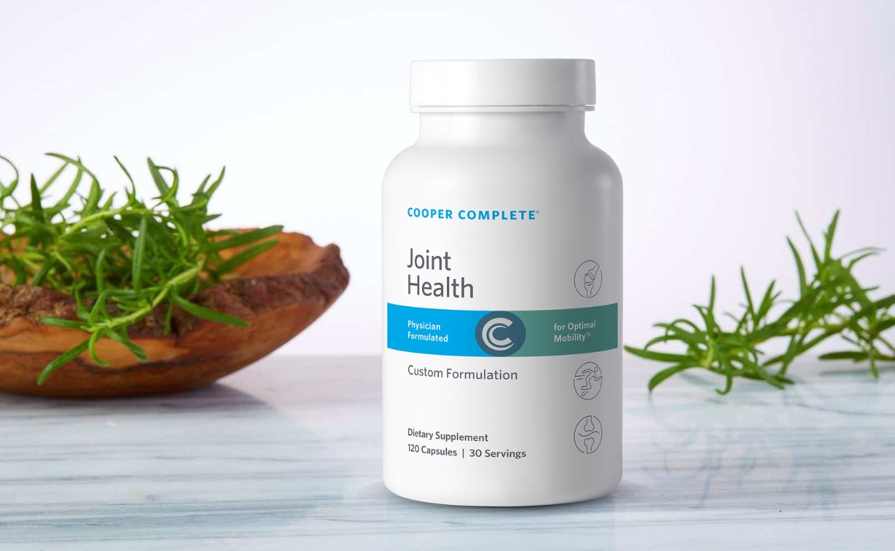 Photo of Cooper Complete Joint Health Supplement bottle on a marble surface with greenery and wood accents