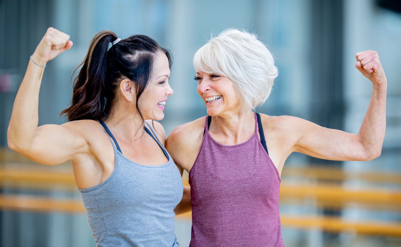 Photo of two women flexing their arms after a workout.