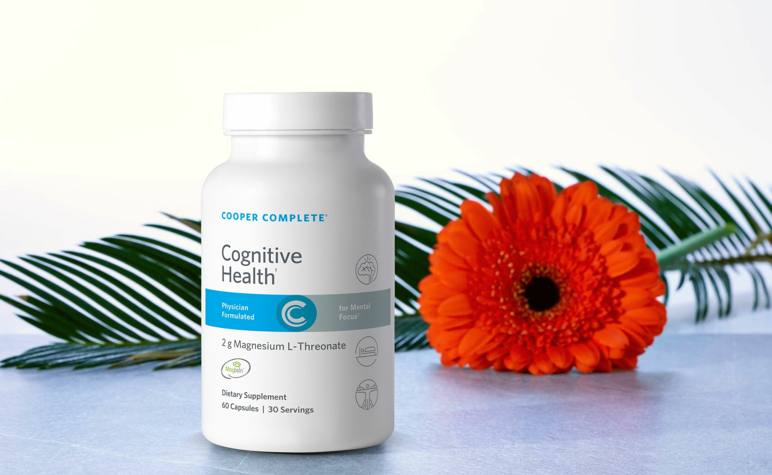 Photo of a bottle of Cooper Compete Cognitive Health magnesium L-threonate on a stone surface with flower and leaf behind it.