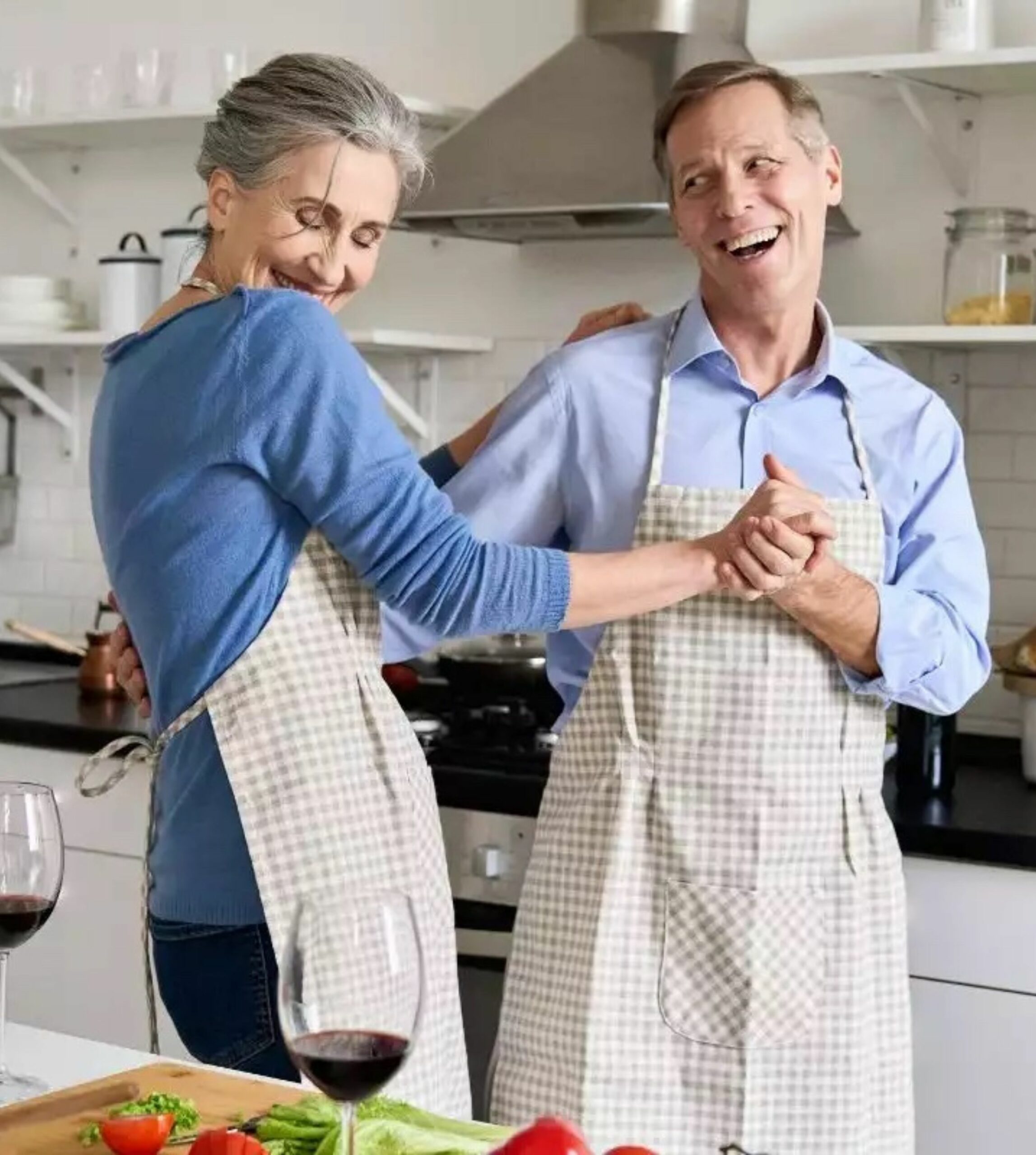 Image of an older middle-aged couple connecting in the kitchen while preparing dinner.