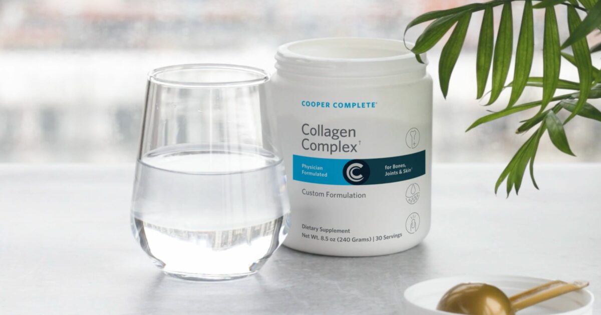 Photo of an open canister of Cooper Complete Collagen Complex beside a glass of water and a scoop.