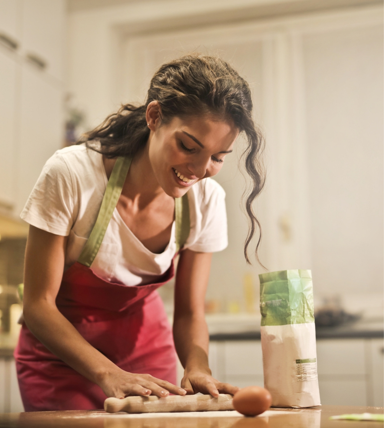 Younger woman baking something with flour and egg.