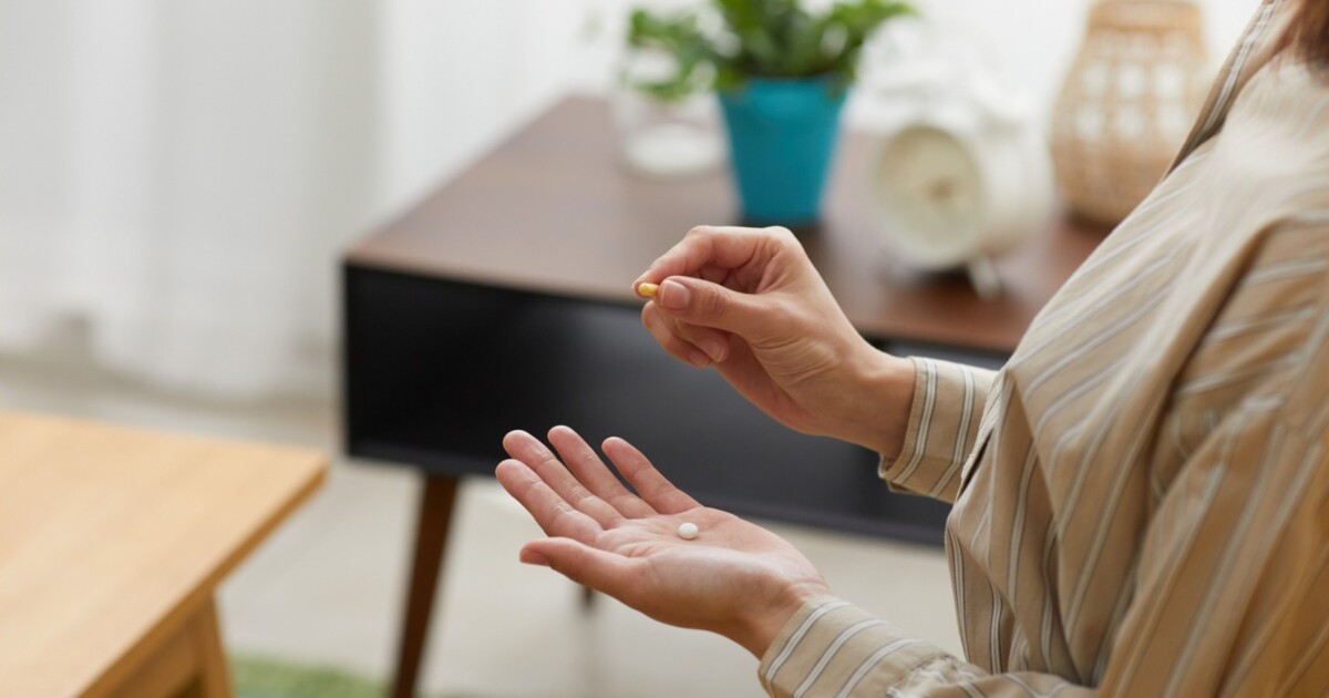 Image of a woman's hands with a pill in each one, presumably to get ready to take.